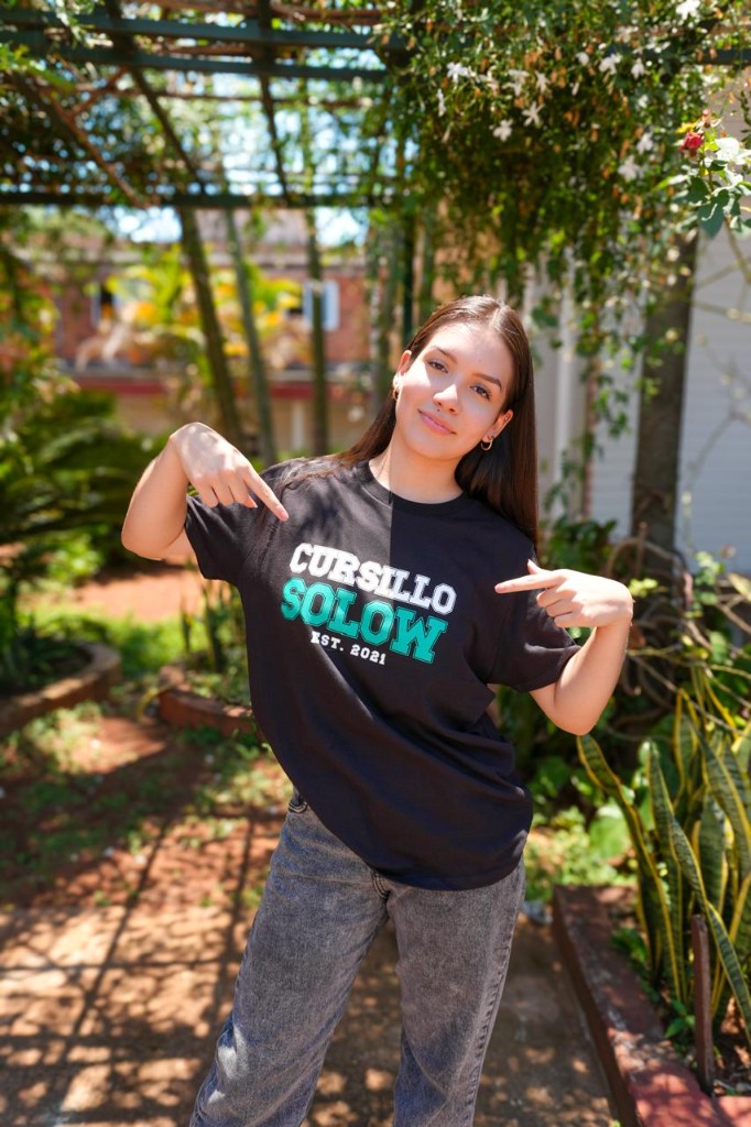 Estudiante del Cursillo Solow señalando la remera institucional